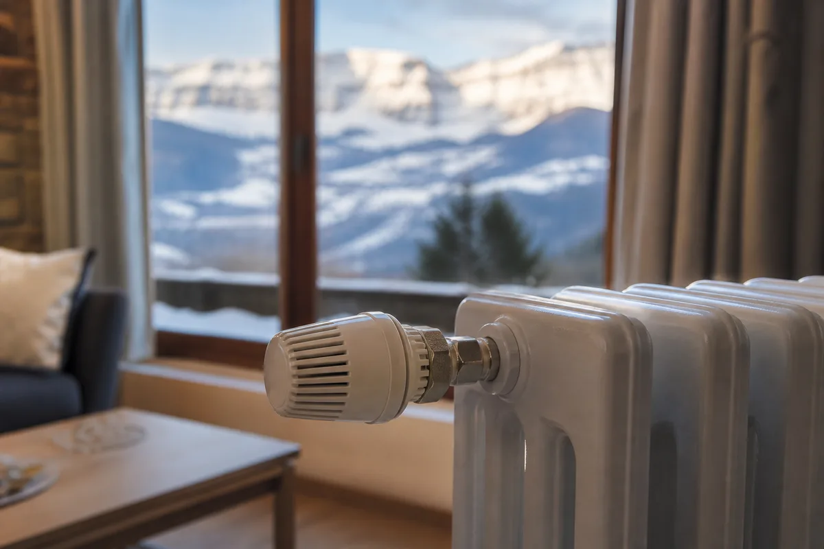 Radiateur et vanne thermostatique dans une maison de vallée savoyarde, lumière naturelle d’hiver
